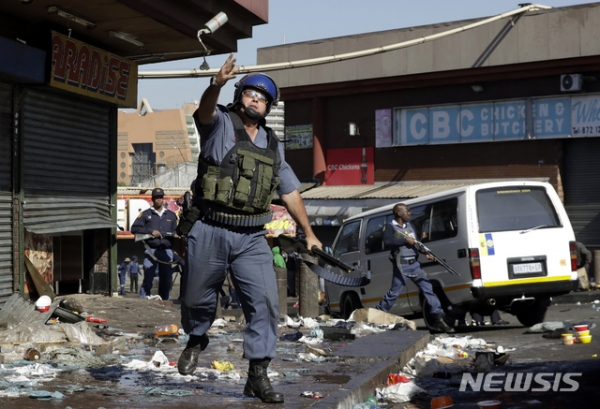 3일(현지시간) 남아프리카공화국 요하네스버그에서 경찰관이 약탈자 진압을 위해 최루탄을 던지는 모습 (사진=뉴시스)